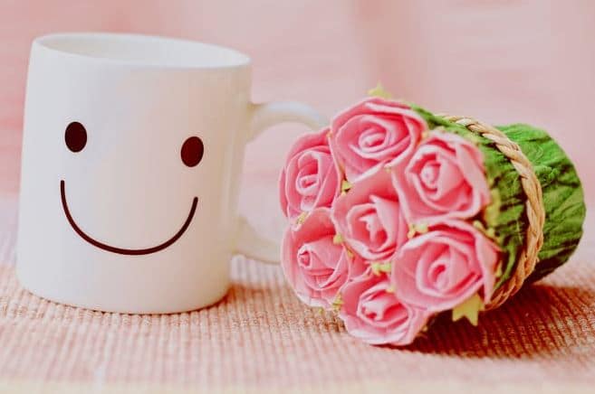 Apartments in Houston’s Energy Corridor A mug with a smiley face next to a bouquet of pink roses, perfect for brightening up your morning coffee routine.